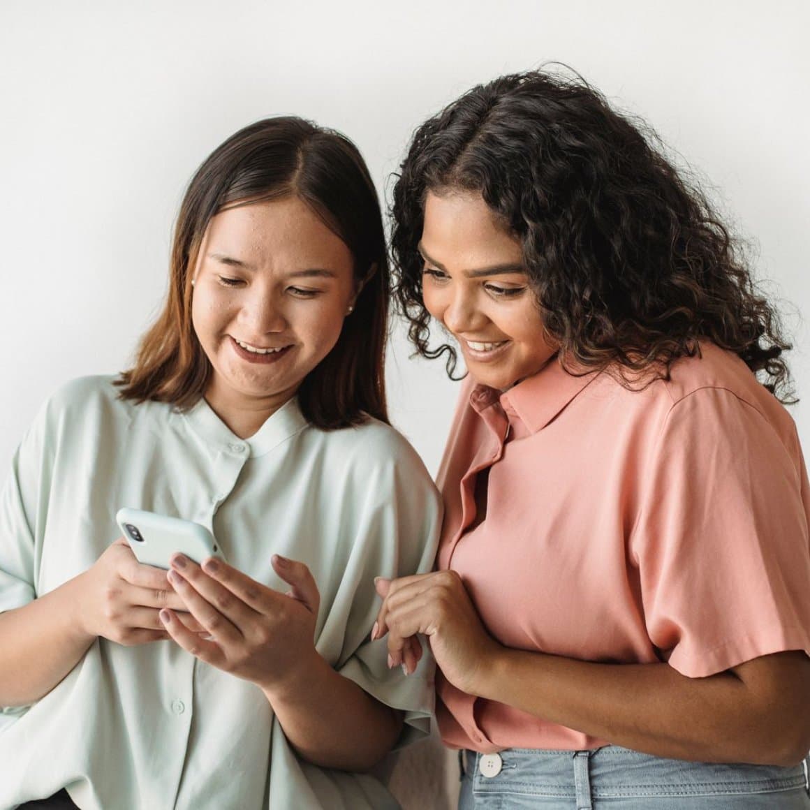 Two colleagues smiling while reading an email on a phone